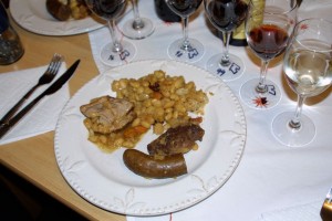 Cassoulet on a plate, surrounded by a halo of glassware